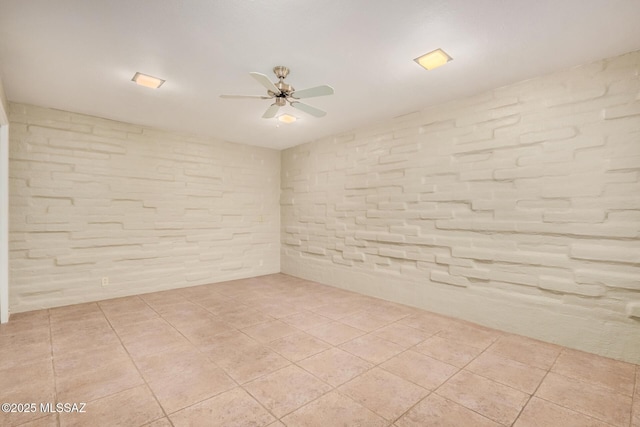 spare room with brick wall, ceiling fan, and light tile patterned flooring
