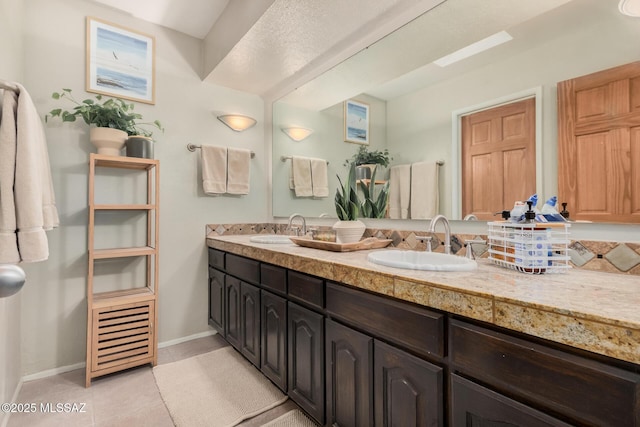 full bathroom featuring baseboards, tile patterned flooring, a sink, and double vanity
