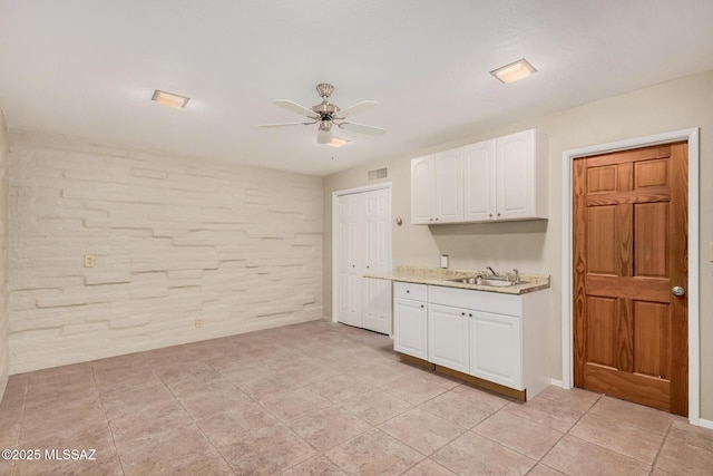 kitchen with white cabinets, light countertops, visible vents, a sink, and ceiling fan