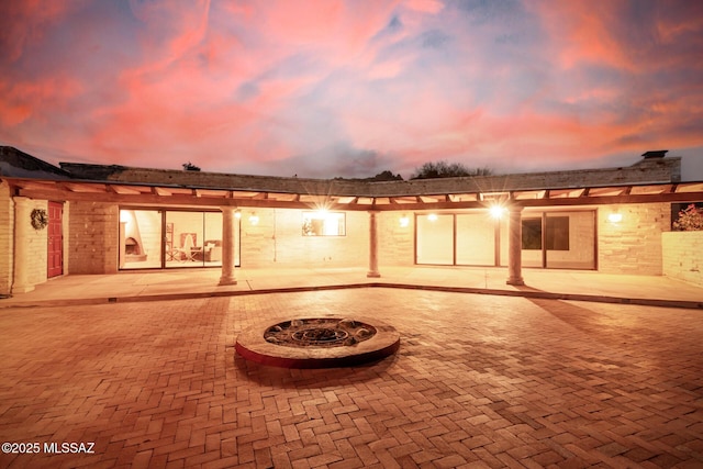 back of property at dusk featuring a patio area and an outdoor fire pit