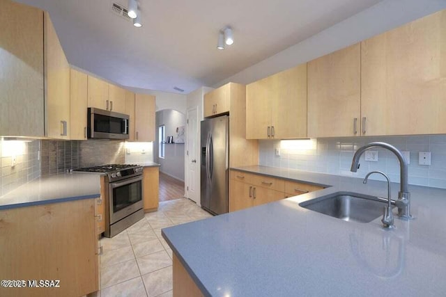 kitchen with a sink, light brown cabinetry, stainless steel appliances, backsplash, and visible vents