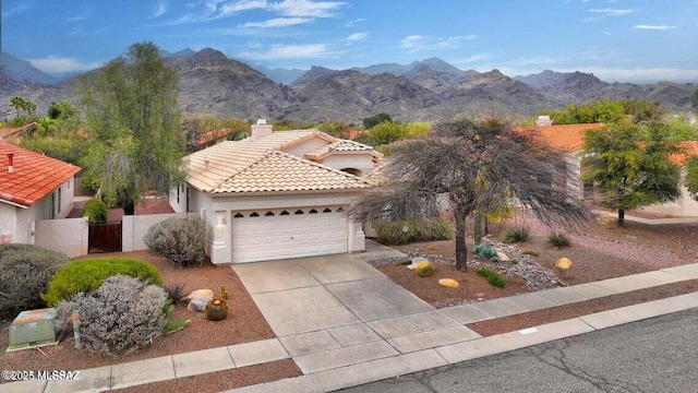 view of front of house with a gate, an attached garage, a tile roof, and a mountain view