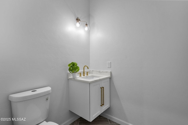 half bath featuring baseboards, toilet, and vanity