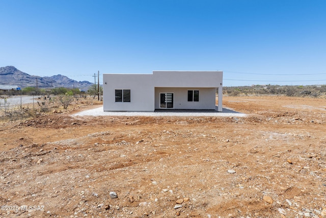 rear view of property with a patio, a mountain view, and stucco siding