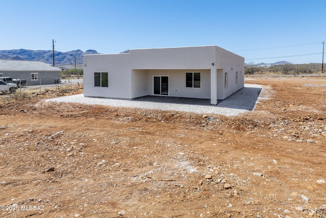 rear view of house featuring a patio area, stucco siding, and a mountain view