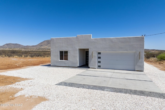 view of front of house featuring stucco siding, concrete driveway, a mountain view, and a garage