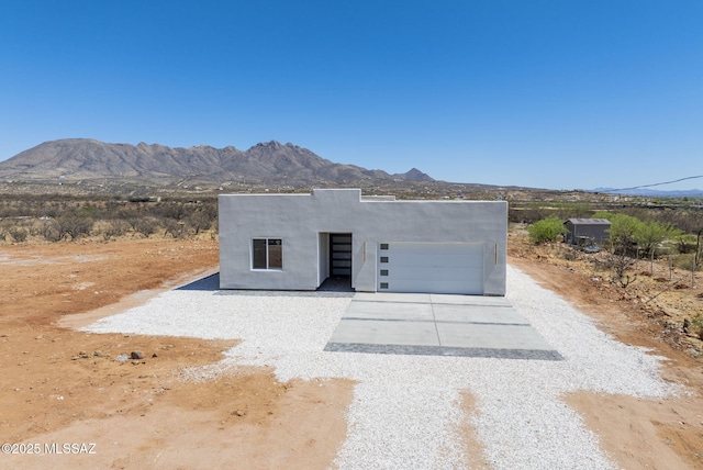 exterior space with a garage, stucco siding, concrete driveway, and a mountain view