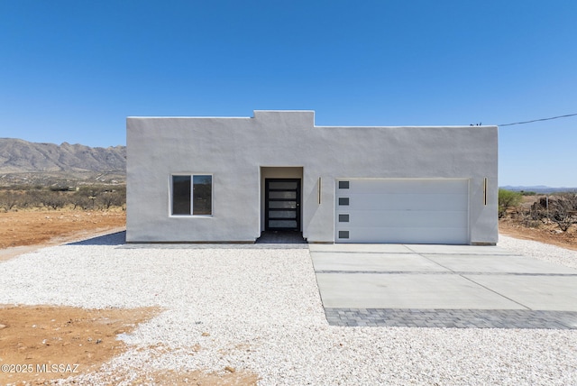 view of front facade with a garage, concrete driveway, stucco siding, and a mountain view