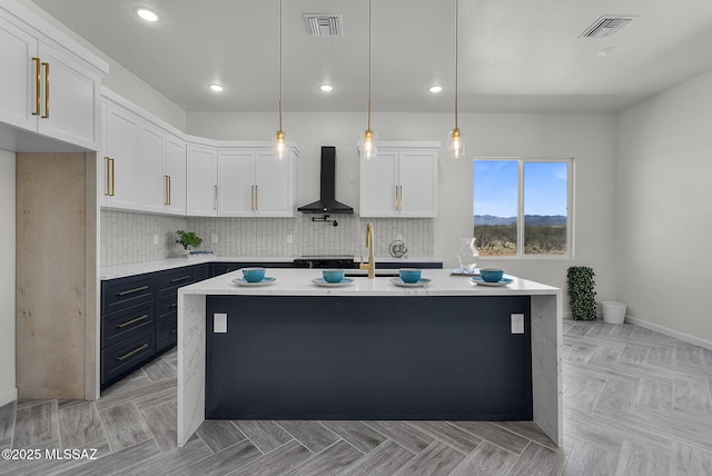 kitchen with white cabinets, backsplash, wall chimney range hood, and visible vents