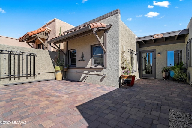 back of property featuring a gate, a patio, stucco siding, and fence