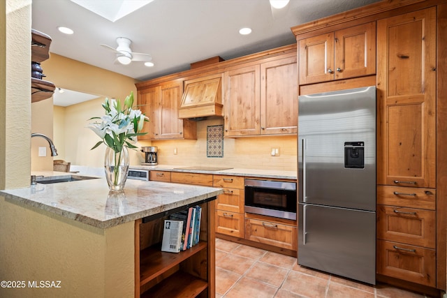 kitchen with black electric cooktop, open shelves, a sink, built in fridge, and custom exhaust hood