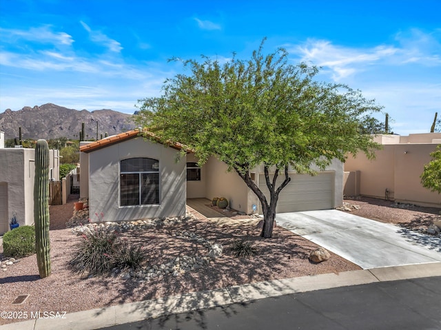 view of front of house featuring driveway, an attached garage, fence, a mountain view, and stucco siding