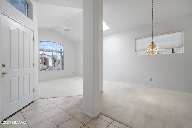 carpeted foyer with tile patterned flooring, vaulted ceiling, and ceiling fan with notable chandelier
