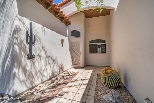 view of exterior entry featuring stucco siding and a tiled roof