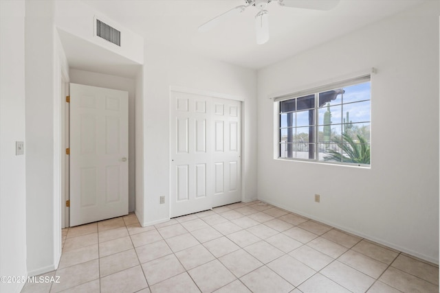 unfurnished bedroom with light tile patterned floors, a closet, visible vents, and a ceiling fan