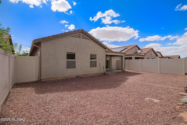 rear view of house with a tile roof, a patio, a fenced backyard, and stucco siding