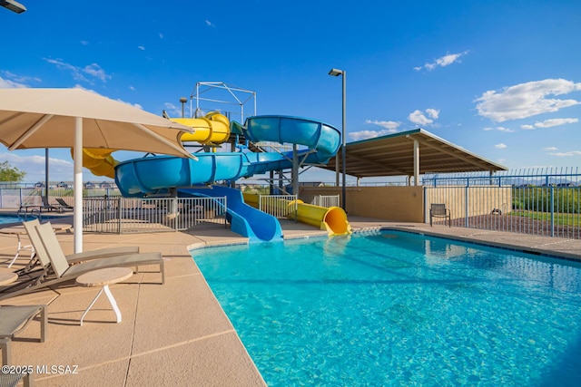 pool with fence, a patio area, and a water slide