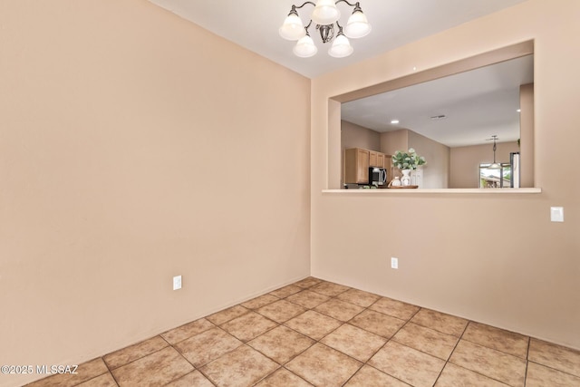 spare room featuring a chandelier and light tile patterned flooring