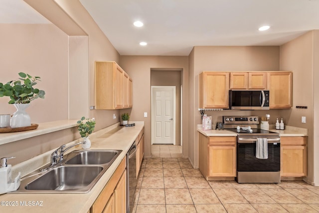 kitchen featuring stainless steel appliances, light countertops, light brown cabinetry, and a sink