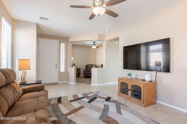 living room featuring a ceiling fan, baseboards, and light tile patterned floors