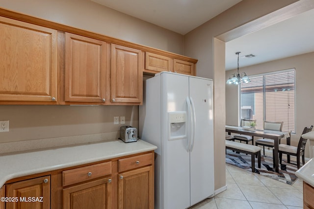 kitchen featuring light countertops, visible vents, light tile patterned flooring, white fridge with ice dispenser, and a notable chandelier