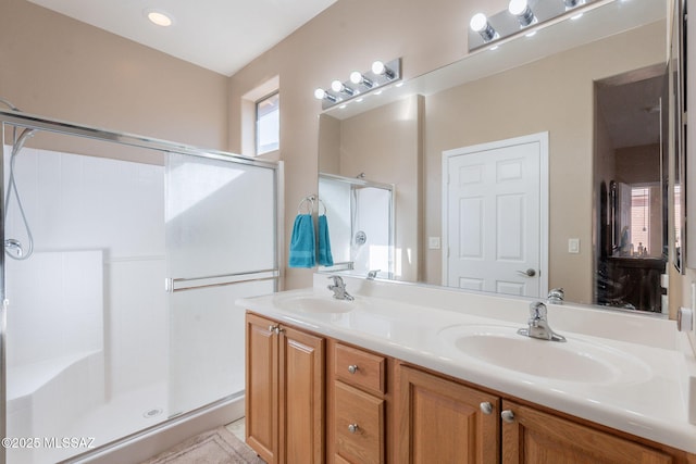bathroom with a sink, a shower stall, and double vanity