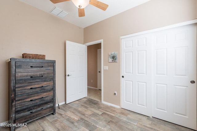 unfurnished bedroom featuring light wood-style flooring, baseboards, visible vents, a closet, and ceiling fan
