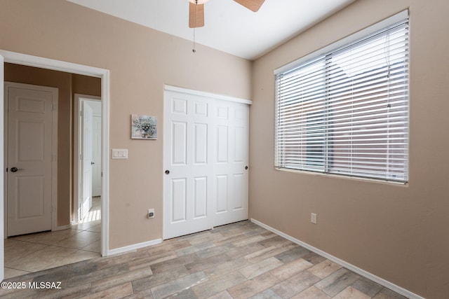 unfurnished bedroom featuring a closet, light wood finished floors, baseboards, and a ceiling fan