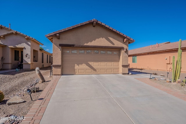 view of front facade with stucco siding, an attached garage, and driveway