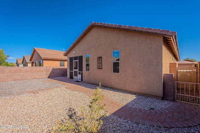 back of property with a gate, fence private yard, a patio area, and stucco siding