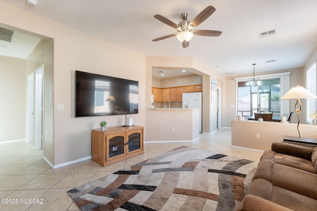 living room with ceiling fan with notable chandelier, baseboards, visible vents, and light tile patterned flooring