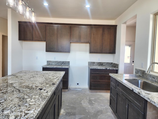 kitchen featuring light stone counters, dark brown cabinets, a sink, hanging light fixtures, and recessed lighting