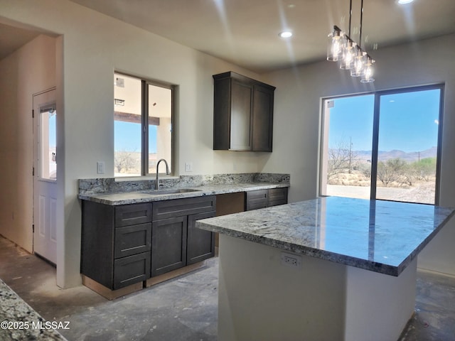 kitchen with unfinished concrete floors, recessed lighting, a sink, decorative light fixtures, and light stone countertops