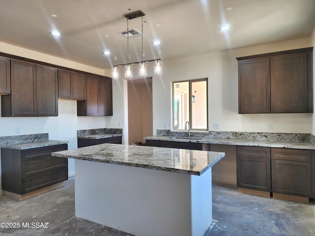 kitchen featuring dark brown cabinetry, visible vents, a sink, and concrete floors
