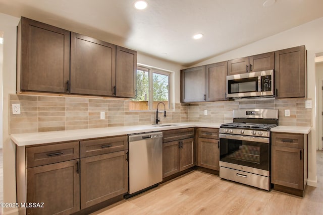 kitchen featuring recessed lighting, light countertops, a sink, light wood-type flooring, and appliances with stainless steel finishes