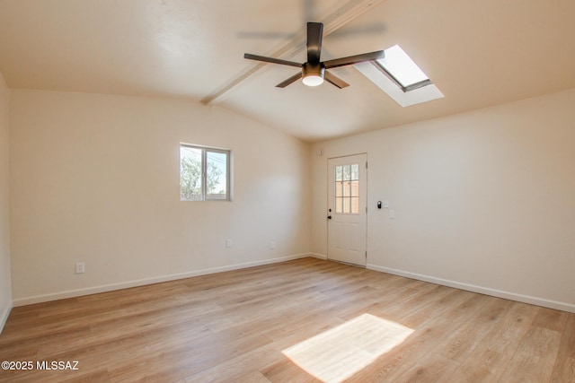 spare room with light wood-style floors, lofted ceiling with skylight, baseboards, and ceiling fan