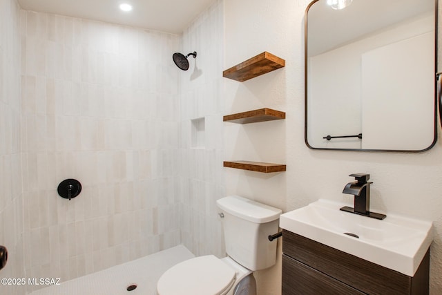 bathroom featuring recessed lighting, vanity, toilet, and tiled shower