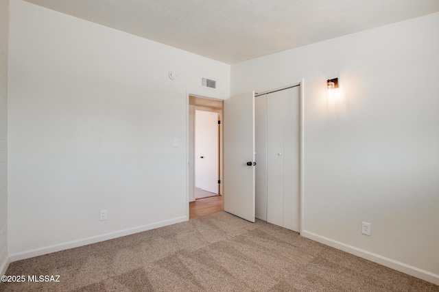 unfurnished bedroom featuring a closet, baseboards, visible vents, and light colored carpet
