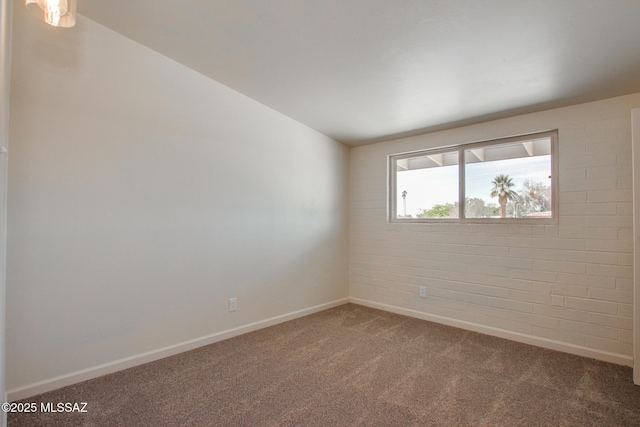 carpeted spare room with vaulted ceiling and baseboards