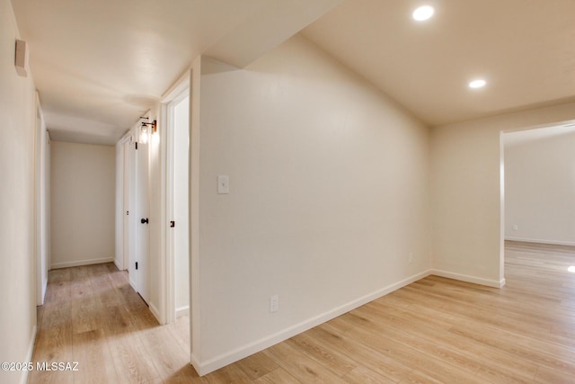 hallway featuring light wood finished floors, baseboards, and recessed lighting