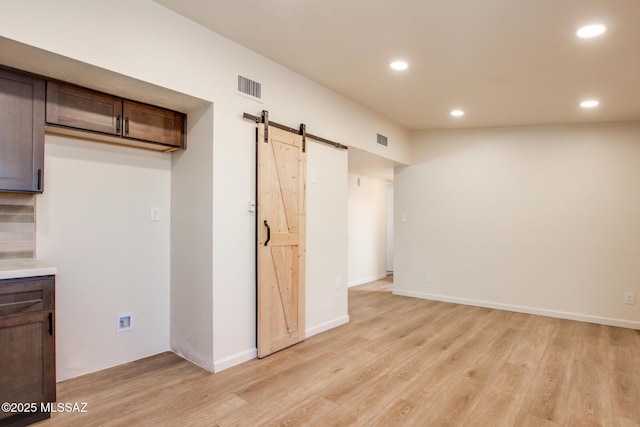 interior space featuring light wood finished floors, visible vents, recessed lighting, and a barn door