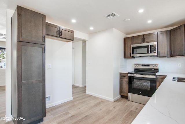 kitchen with dark brown cabinets, light wood-style flooring, visible vents, and appliances with stainless steel finishes