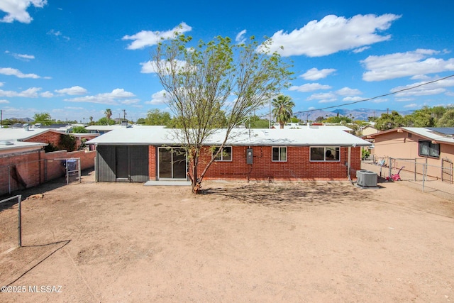 back of property with brick siding, a fenced backyard, and central AC unit
