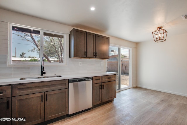 kitchen with dishwasher, a sink, backsplash, and light wood-style flooring