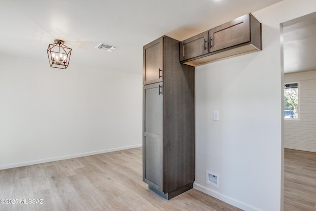 corridor with baseboards, light wood-style flooring, visible vents, and a chandelier