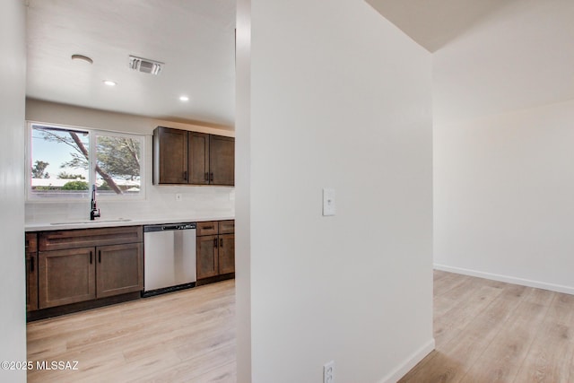 kitchen featuring light wood finished floors, light countertops, dishwasher, visible vents, and a sink