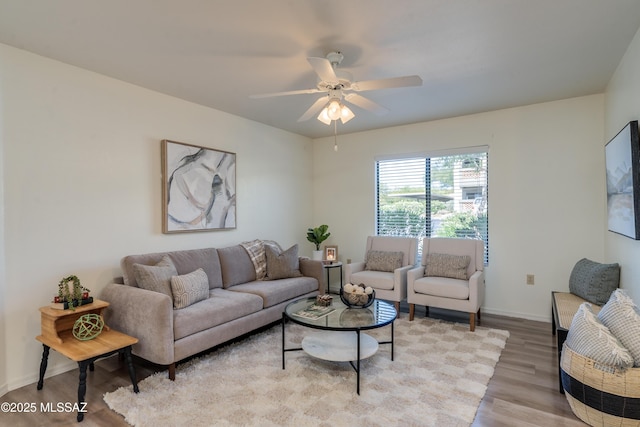 living area featuring light wood-style floors, baseboards, and ceiling fan