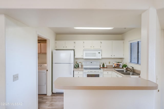 kitchen featuring a sink, white cabinets, a peninsula, washer / dryer, and white appliances