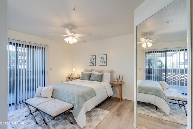 bedroom with baseboards, access to exterior, multiple windows, and light wood-style floors