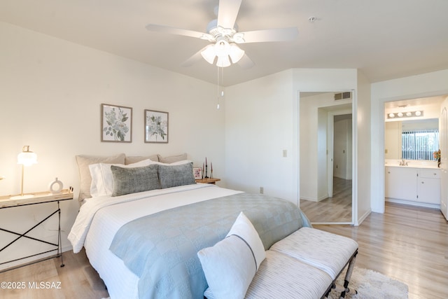 bedroom with visible vents, a sink, light wood-style flooring, and connected bathroom